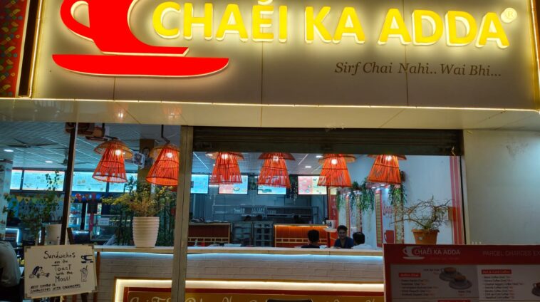 Chaei Ka Adda cafe storefront with bright yellow signage, red tea cup logo, and a menu board showing Indian chai and snacks.