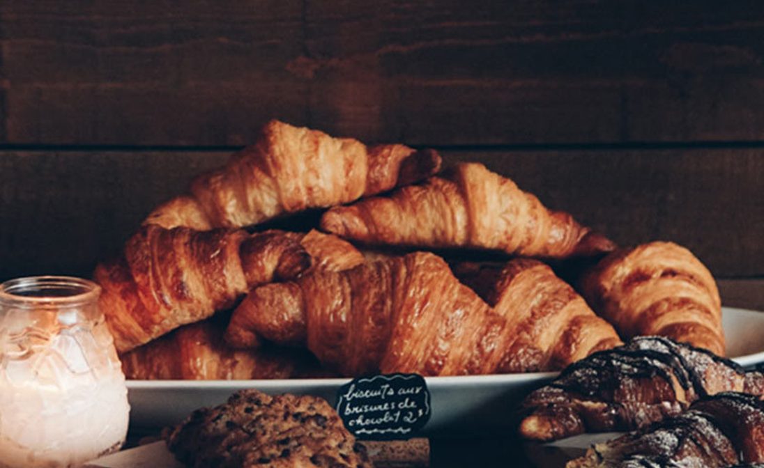h4-blog5 Gourmet bakery selection including plain croissants, chocolate chip biscuits, and powdered pastries with rustic signage